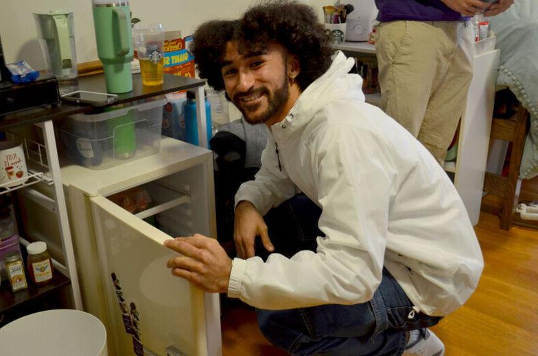 一个男学生微笑着打开迷你冰箱